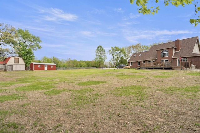 view of grassy yard featuring a deck and an outbuilding