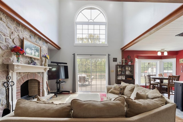 living area with a high ceiling, healthy amount of natural light, and a brick fireplace