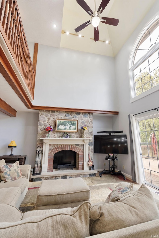 living area featuring a high ceiling, ceiling fan, a stone fireplace, baseboards, and recessed lighting