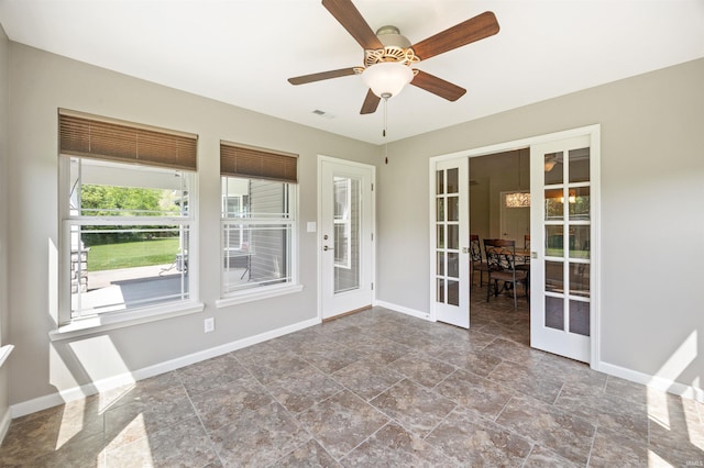 empty room with french doors, stone finish flooring, baseboards, and ceiling fan