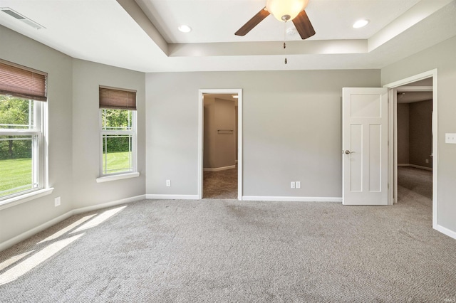unfurnished bedroom featuring carpet flooring, a tray ceiling, and baseboards