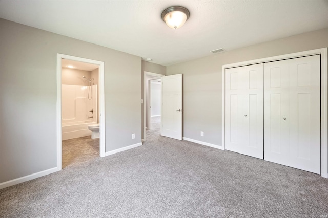 unfurnished bedroom featuring carpet floors, baseboards, a closet, and connected bathroom