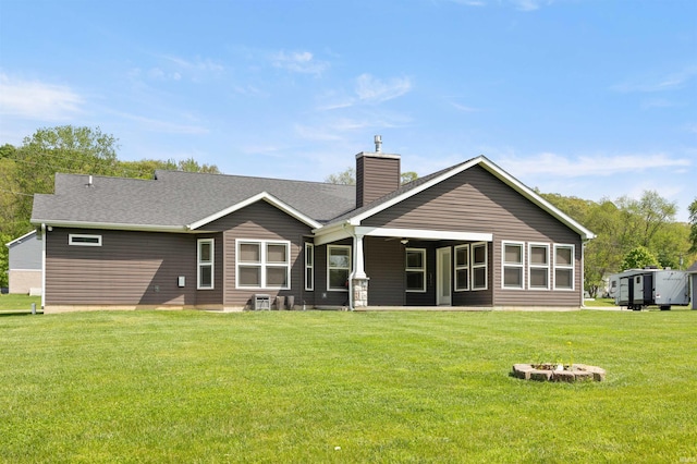 back of house featuring a chimney, a yard, a fire pit, and central AC unit