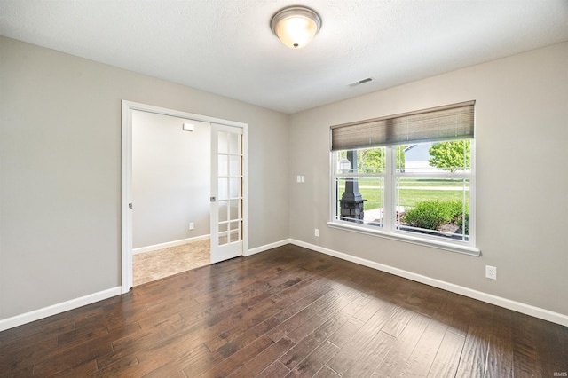 spare room with baseboards, dark wood finished floors, and french doors