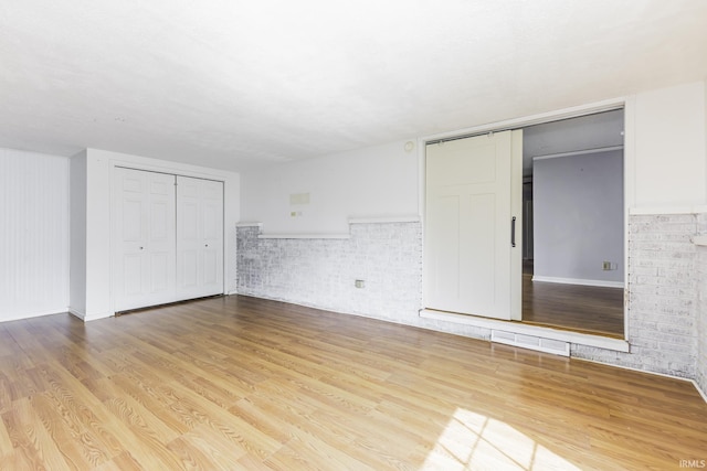 unfurnished bedroom featuring wood finished floors, baseboards, and two closets