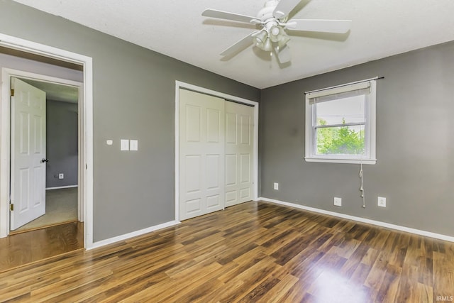 unfurnished bedroom featuring wood finished floors, baseboards, a closet, and a ceiling fan