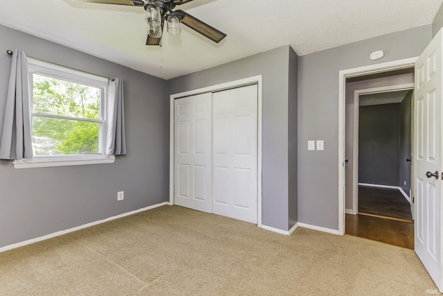 unfurnished bedroom featuring carpet floors, a closet, baseboards, and a ceiling fan