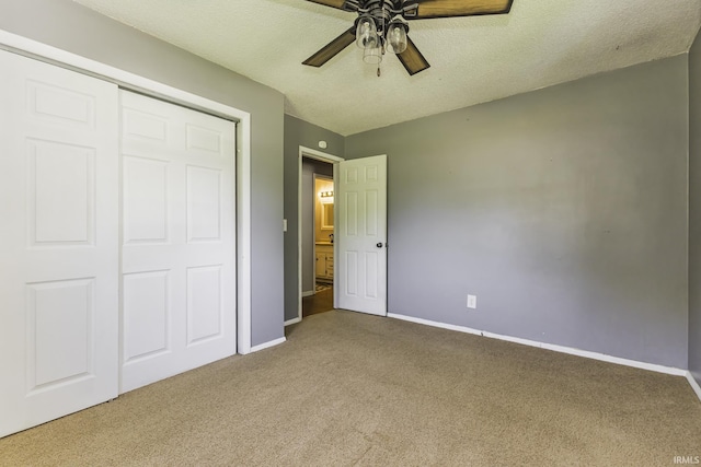 unfurnished bedroom featuring carpet, baseboards, a closet, a ceiling fan, and a textured ceiling