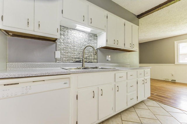 kitchen with dishwasher, a sink, light countertops, a textured ceiling, and white cabinetry