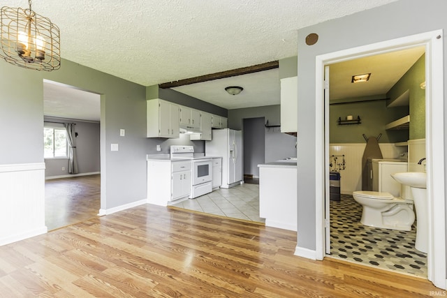 kitchen with white appliances, light wood-style floors, light countertops, a textured ceiling, and under cabinet range hood