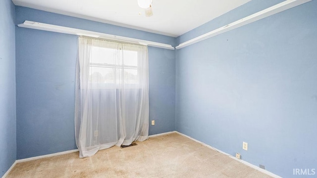 carpeted empty room featuring baseboards