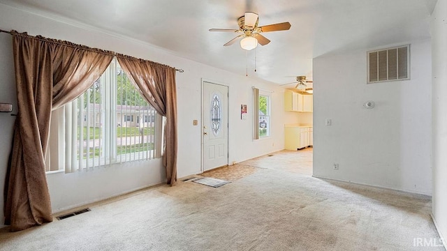 entrance foyer featuring healthy amount of natural light, ceiling fan, and carpet flooring