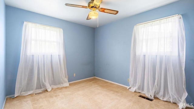 carpeted empty room with a ceiling fan and baseboards