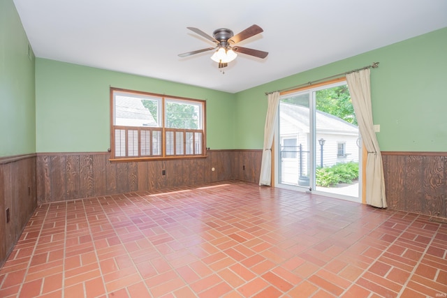 927 S Lombard Ave, Evansville, IN 47714 - spare room featuring a wainscoted wall, wooden walls, a ceiling fan, and brick patterned floors