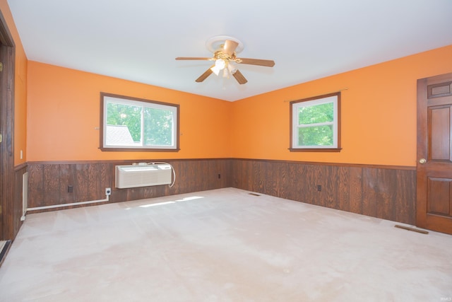 927 S Lombard Ave, Evansville, IN 47714 - carpeted spare room featuring wainscoting, plenty of natural light, wood walls, a ceiling fan, and a wall unit AC