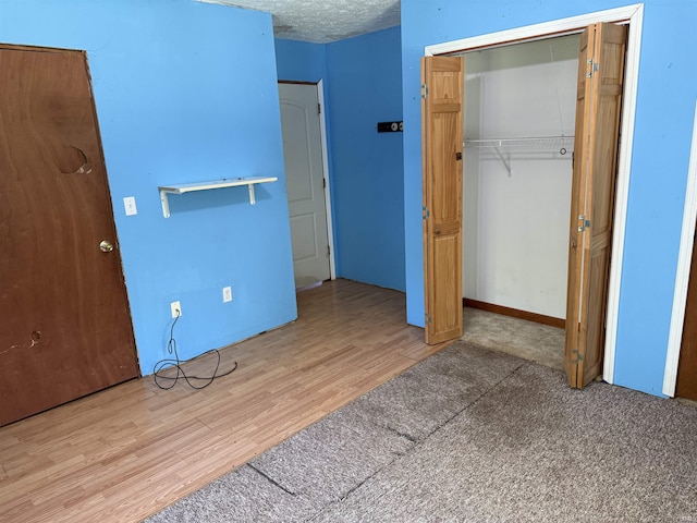 unfurnished bedroom featuring a closet, wood finished floors, and a textured ceiling