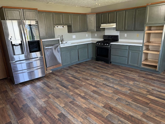 kitchen featuring stainless steel appliances, a sink, dark wood-type flooring, under cabinet range hood, and a textured ceiling