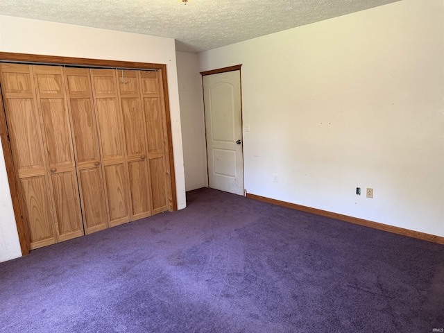 unfurnished bedroom featuring dark colored carpet, a textured ceiling, a closet, and baseboards