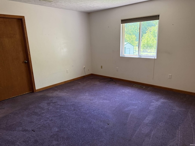carpeted empty room with a textured ceiling and baseboards