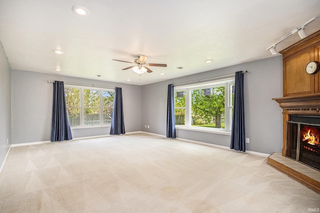 unfurnished living room with light colored carpet, ceiling fan, a large fireplace, plenty of natural light, and recessed lighting