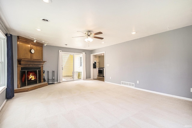 unfurnished living room featuring ceiling fan, light colored carpet, a fireplace, baseboards, and recessed lighting