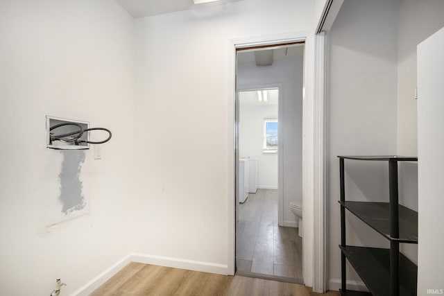hall with light wood-style floors and baseboards