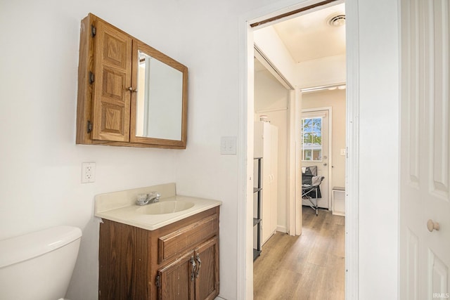 half bathroom with wood finished floors, vanity, and toilet