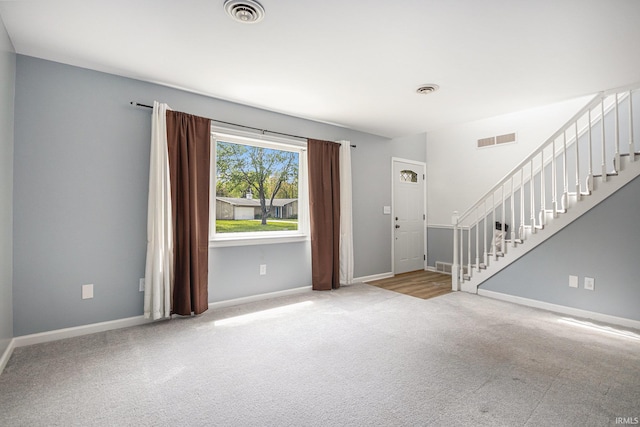 carpeted foyer entrance with stairs and baseboards