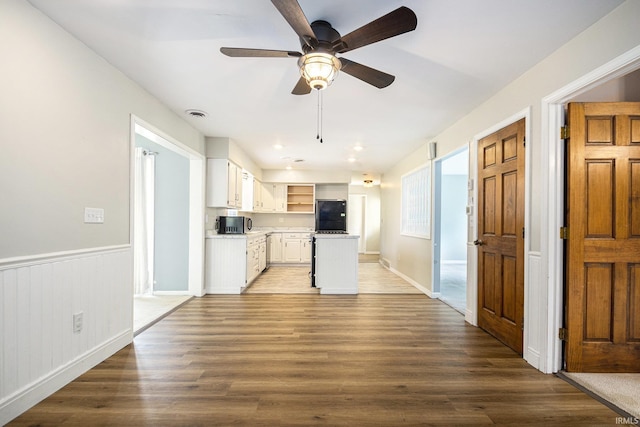 kitchen with white cabinetry, a ceiling fan, open shelves, stainless steel microwave, and wood finished floors