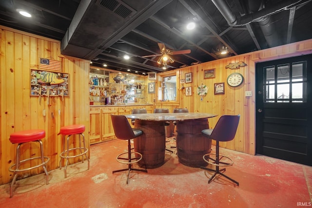 indoor dry bar featuring concrete floors, wooden walls, and ceiling fan