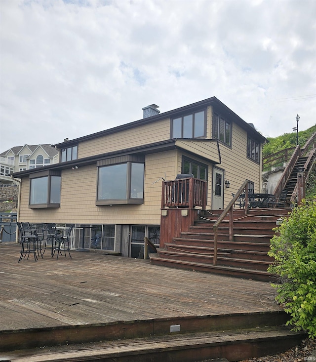back of house featuring stairs, a deck, and a chimney