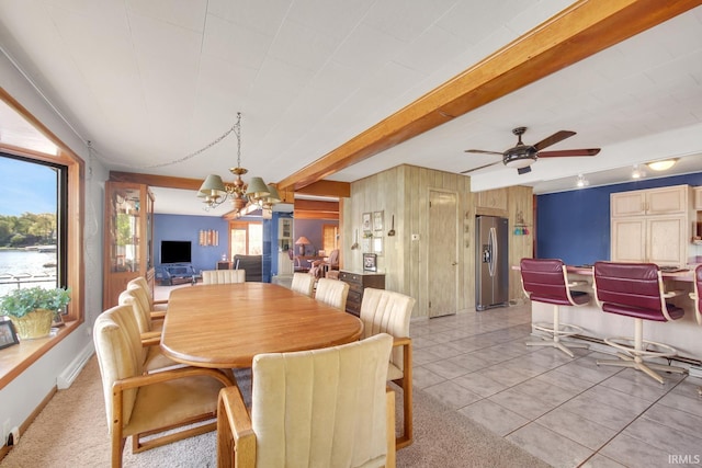 dining area featuring a chandelier, wood walls, ceiling fan, light tile patterned flooring, and beamed ceiling