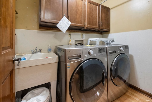 washroom featuring washing machine and dryer, cabinet space, and light wood finished floors