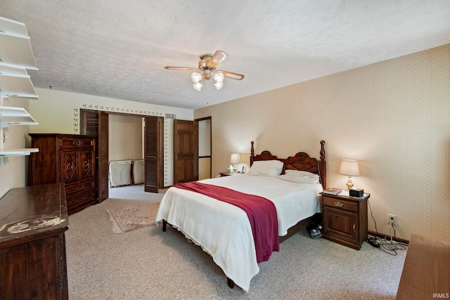 bedroom featuring light colored carpet, wallpapered walls, a ceiling fan, and a textured ceiling