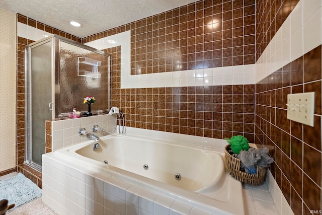 full bathroom featuring a jetted tub, a textured ceiling, a stall shower, and tile walls
