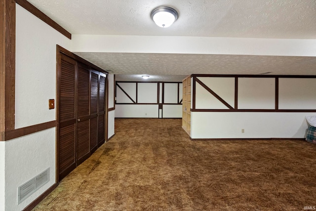 finished below grade area with a textured ceiling and carpet flooring