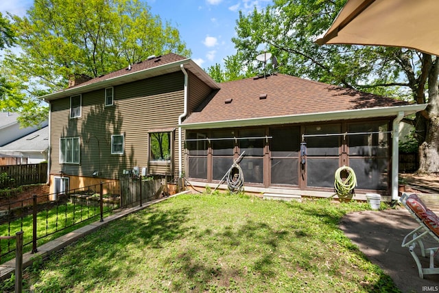 rear view of property featuring a sunroom and a shingled roof