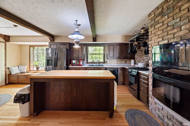 kitchen featuring wooden counters, black appliances, light wood-style flooring, a textured ceiling, and a kitchen island