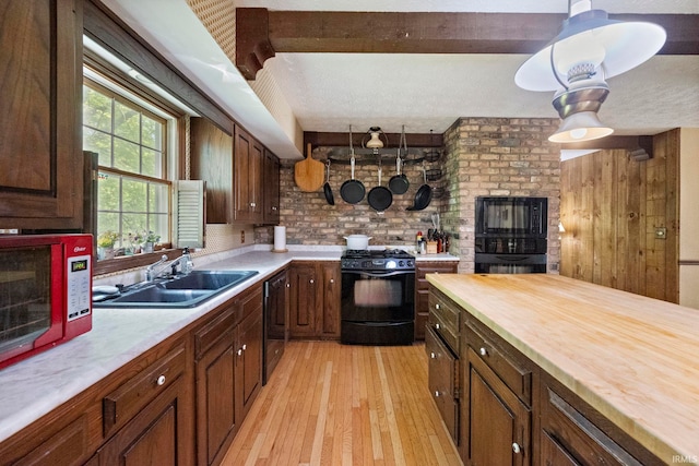 kitchen featuring black range with gas stovetop, a sink, light wood-style floors, butcher block counters, and dishwashing machine