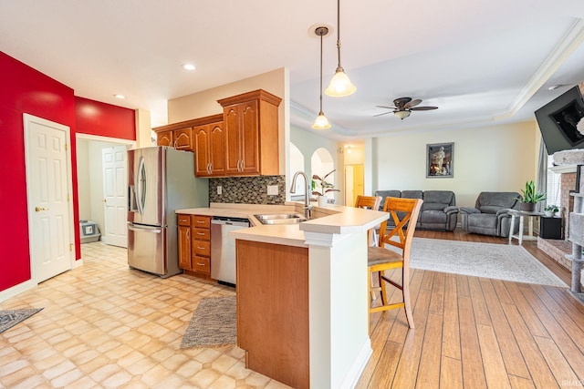kitchen with a sink, stainless steel appliances, a peninsula, a breakfast bar, and light countertops