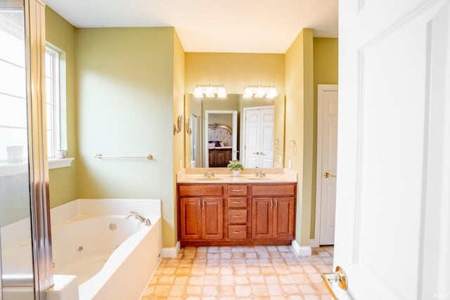 full bath featuring plenty of natural light, a tub with jets, double vanity, and baseboards