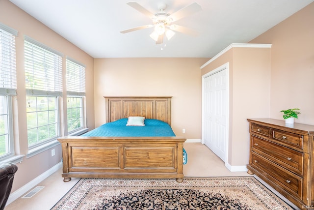 bedroom with baseboards, light colored carpet, ceiling fan, and a closet