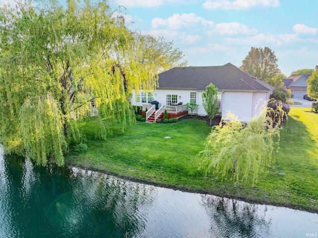 rear view of property with a yard, a deck with water view, and an attached garage