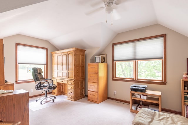 home office with lofted ceiling, healthy amount of natural light, light colored carpet, baseboards, and a ceiling fan