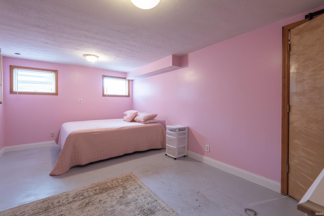 bedroom with concrete flooring, a textured ceiling, and baseboards