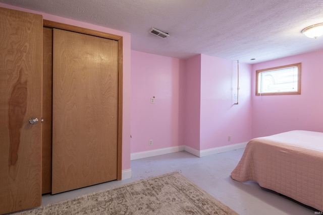 bedroom with concrete flooring, a textured ceiling, and baseboards