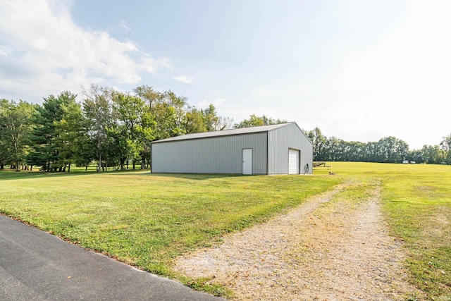 view of grassy yard featuring driveway, an outbuilding, a garage, and a pole building