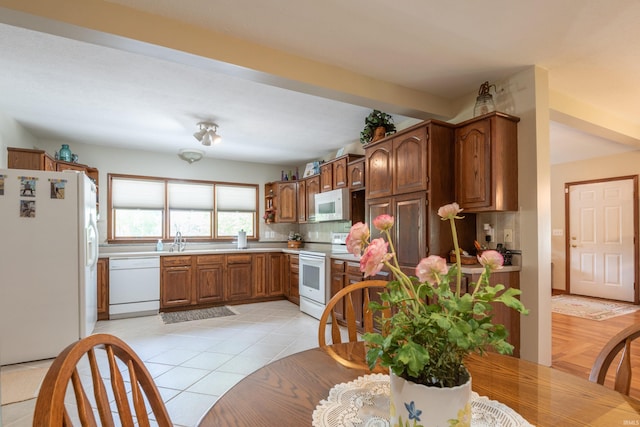kitchen featuring white appliances, a sink, light countertops, backsplash, and light tile patterned floors