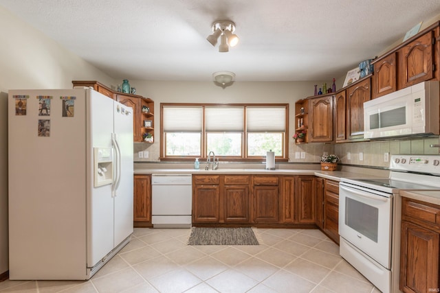 kitchen featuring white appliances, open shelves, brown cabinets, light countertops, and a sink