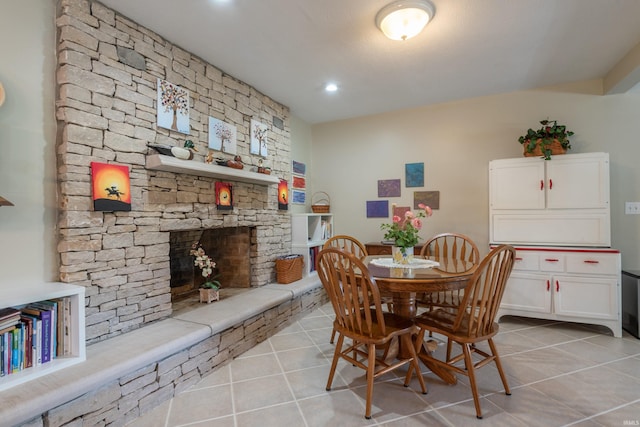 dining space with light tile patterned floors and a stone fireplace